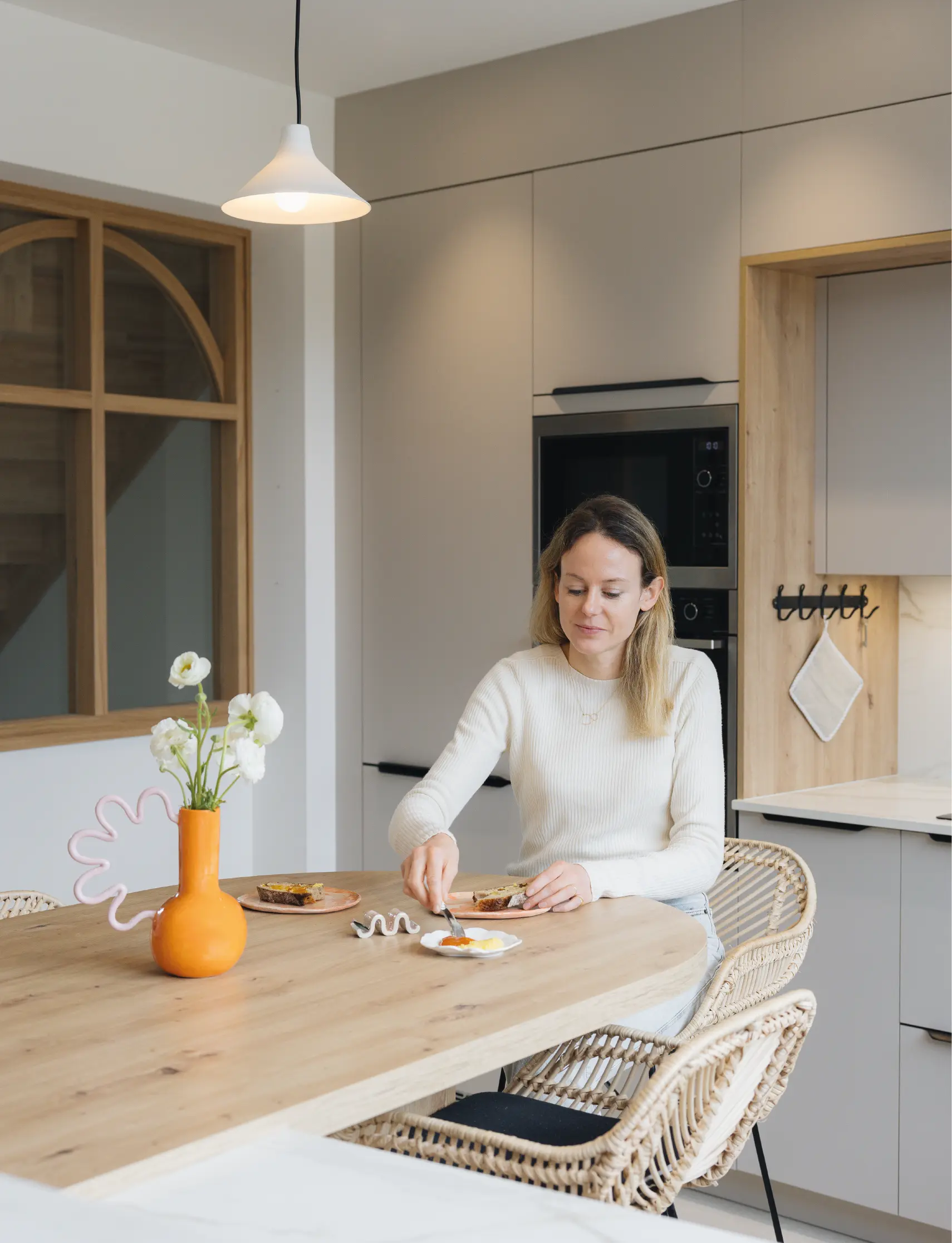 Cuisine contemporaine avec table en bois et décoration moderne, femme savourant un repas.