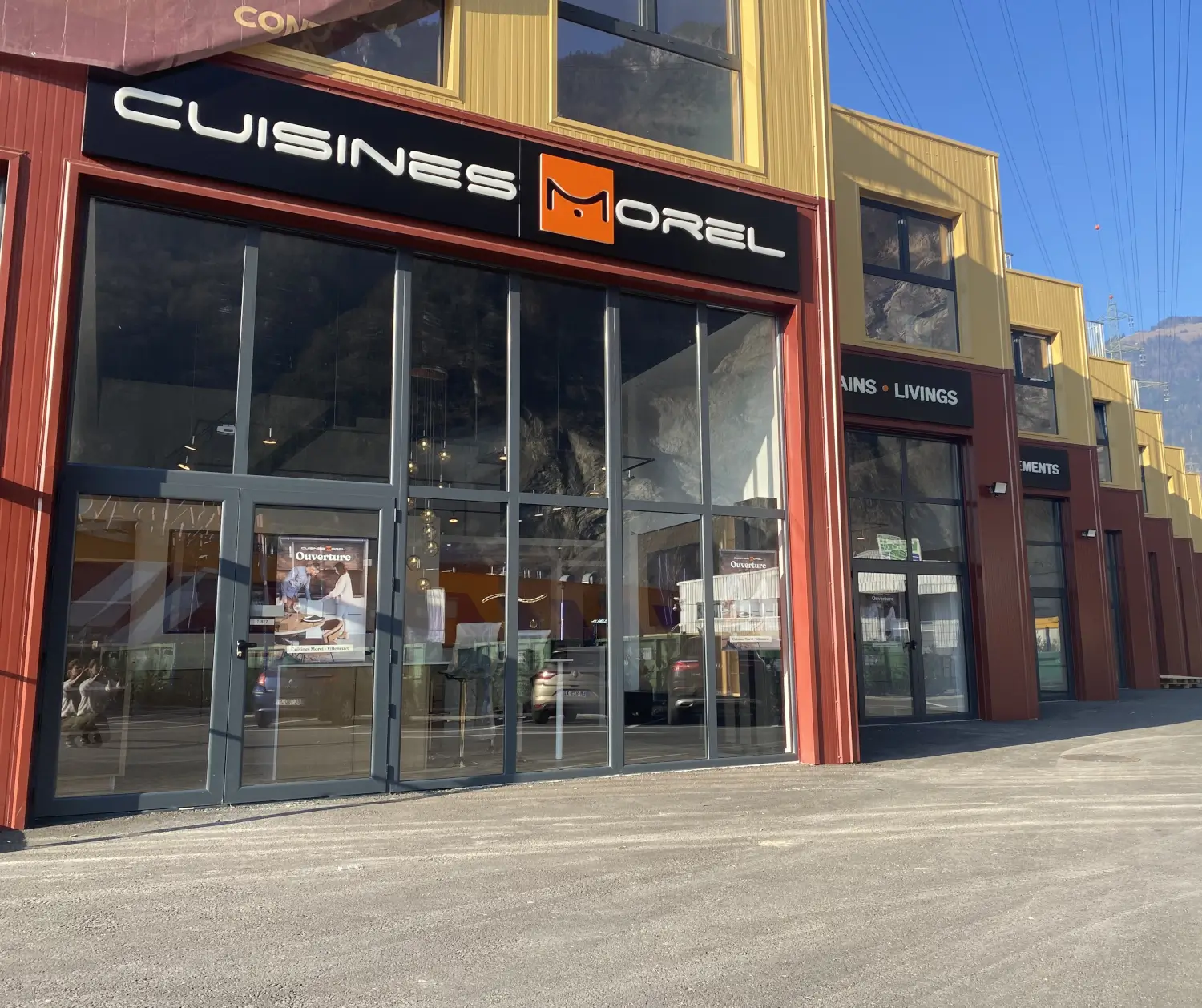 Extérieur d'un magasin Cuisines Morel à Villeneuve en Suisse avec logo visible et panneaux modernes.